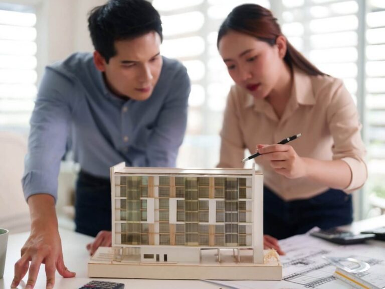 Architecture firm website design: two architects reviewing a scale model of a mid-rise building at a desk with drawings