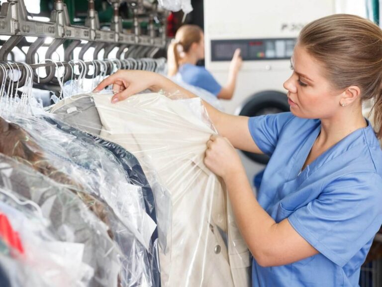 Dry cleaner website design: dry cleaning attendant checking a freshly cleaned coat on the garment conveyor rail