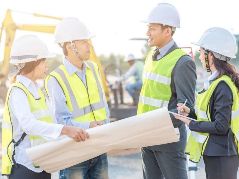 Engineering firm website design: engineers in hard hats and safety vests reviewing project drawings together on an active job site