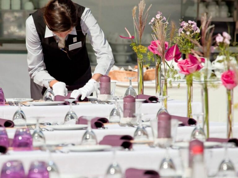 Event planner website design: event staff setting banquet tables with plum napkins, candles and pink floral centerpieces