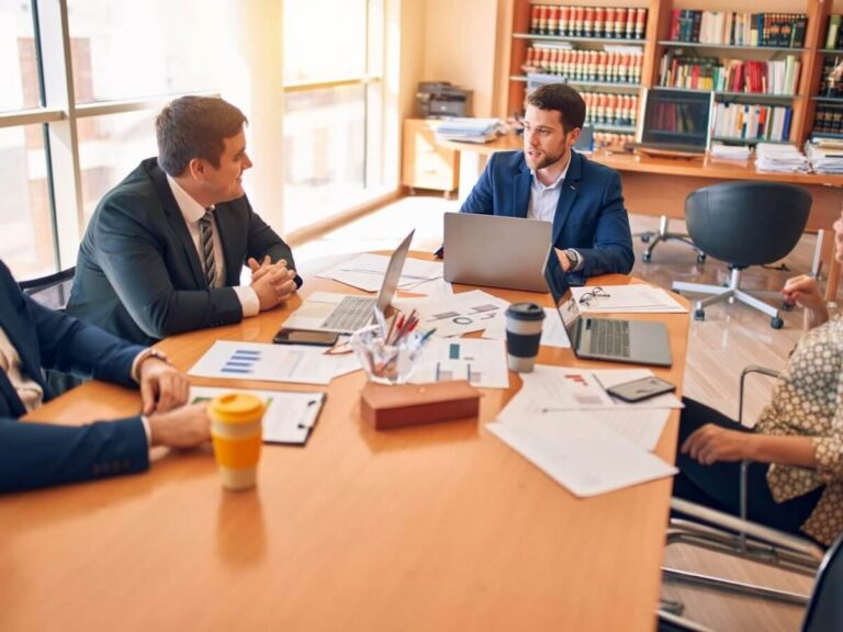 Government contractor website design: proposal team reviewing reports and charts around a conference table with laptops and documents