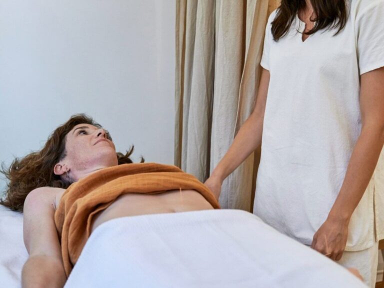 Holistic health practice website design: holistic practitioner attending to a relaxed client on a treatment table during an acupuncture session