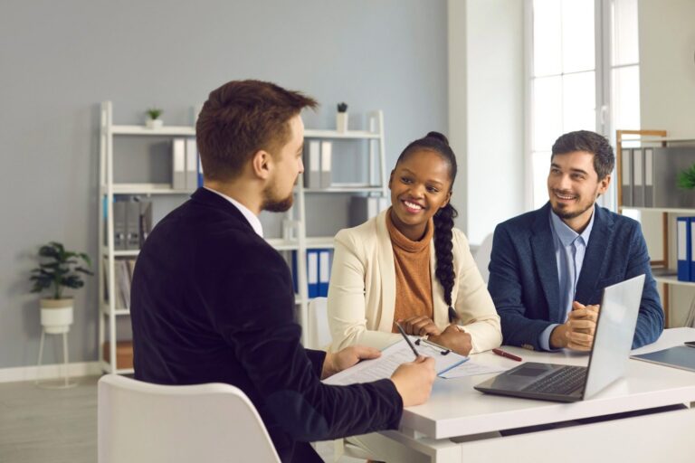 Insurance agent reviewing a policy with a smiling couple at his desk