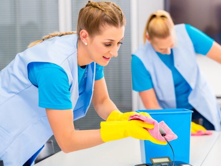 Janitorial company website design: commercial cleaning crew in uniforms and gloves wiping down desks in an office