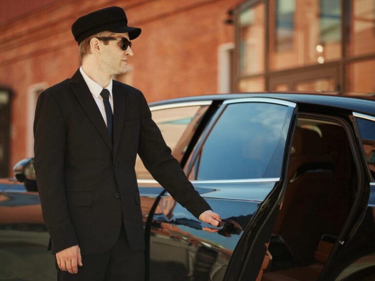Limo company website design: uniformed chauffeur in a cap opening the rear door of a black luxury car outside a brick building