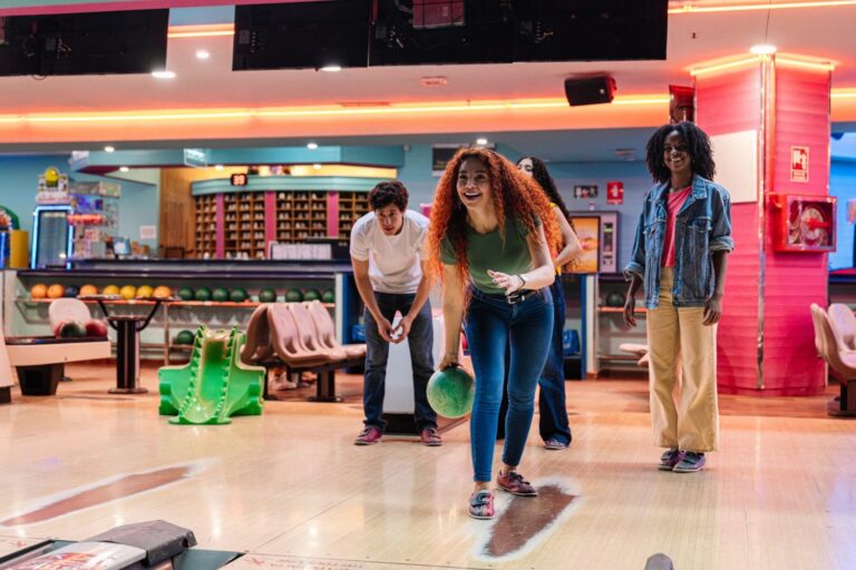 Friends cheering as a woman bowls at a bowling alley