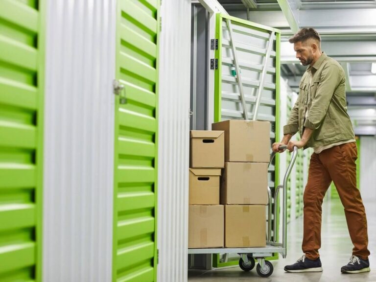 Self storage website design: customer wheeling a cart of moving boxes into an indoor self storage unit