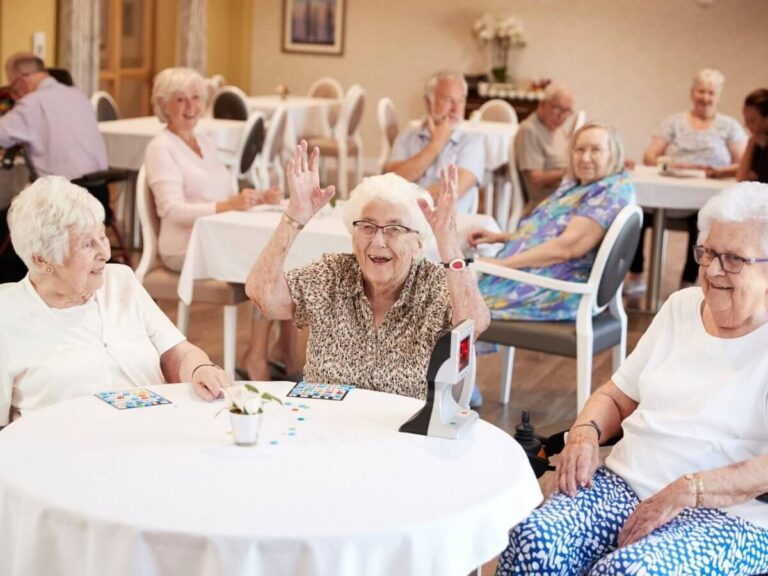 Senior living website design: smiling residents playing bingo together in the bright lounge of a senior living community